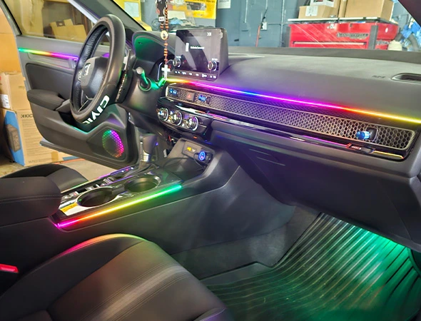 Car interior with vibrant LED strip lighting across the dashboard, center console, and door, creating a colorful, futuristic ambiance.